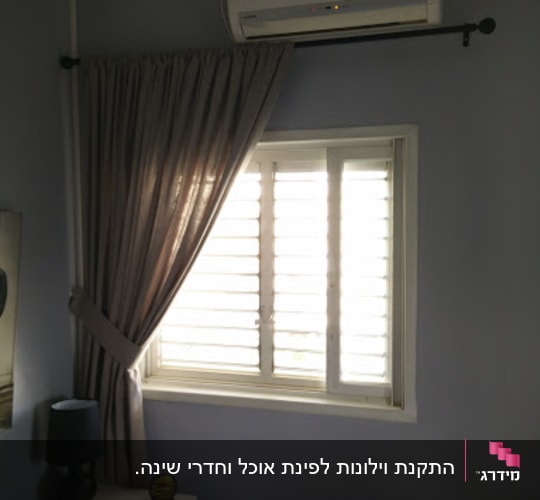 וילון אפור תלוי על מוט מעל חלון